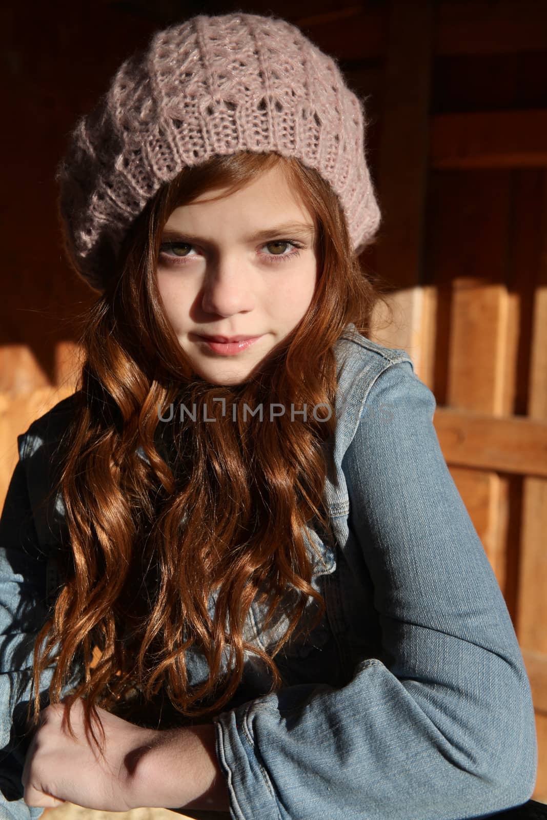 Winter girl leaning against a wooden fence 