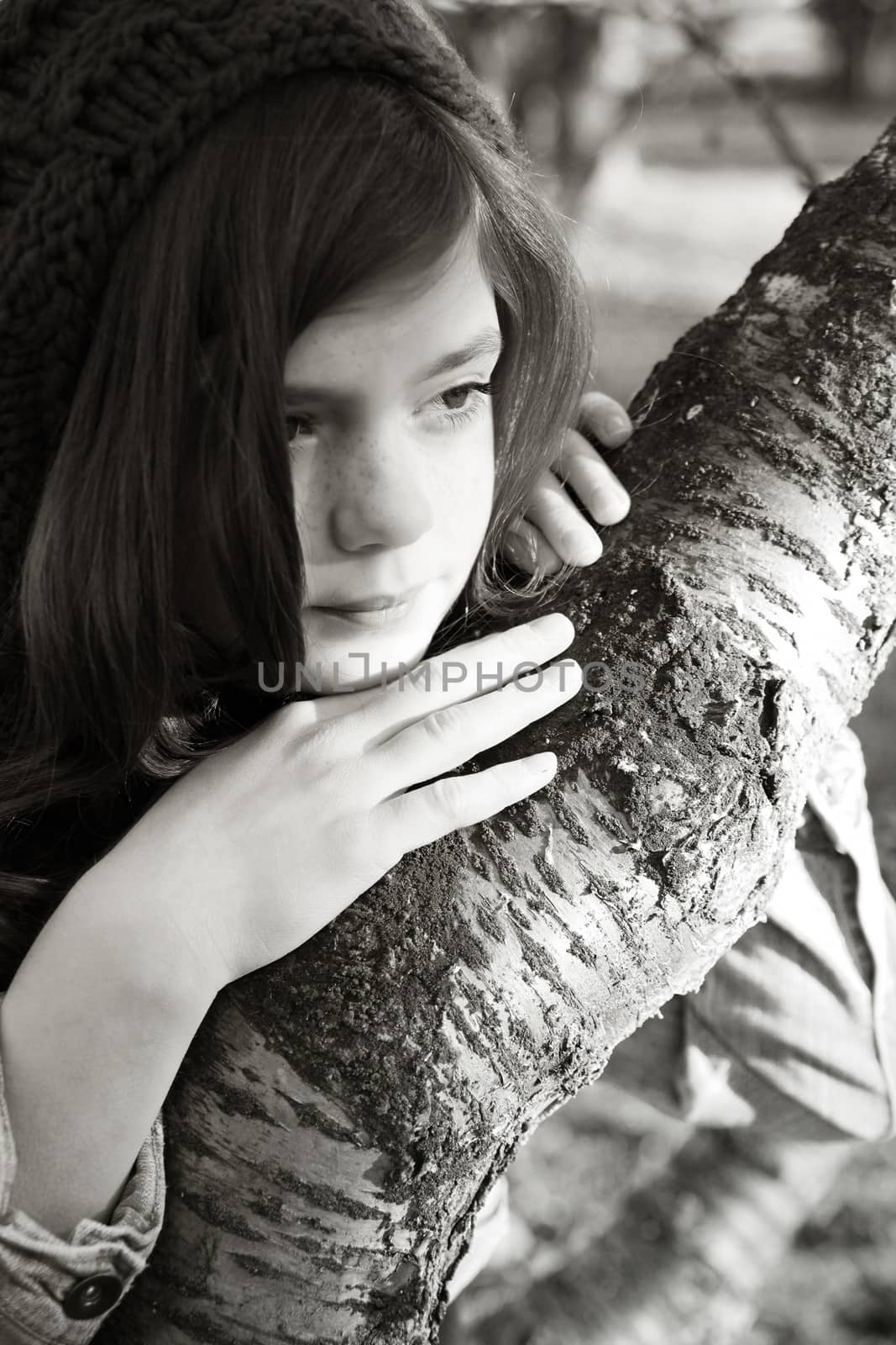 Teen girl leaning against a tree branch