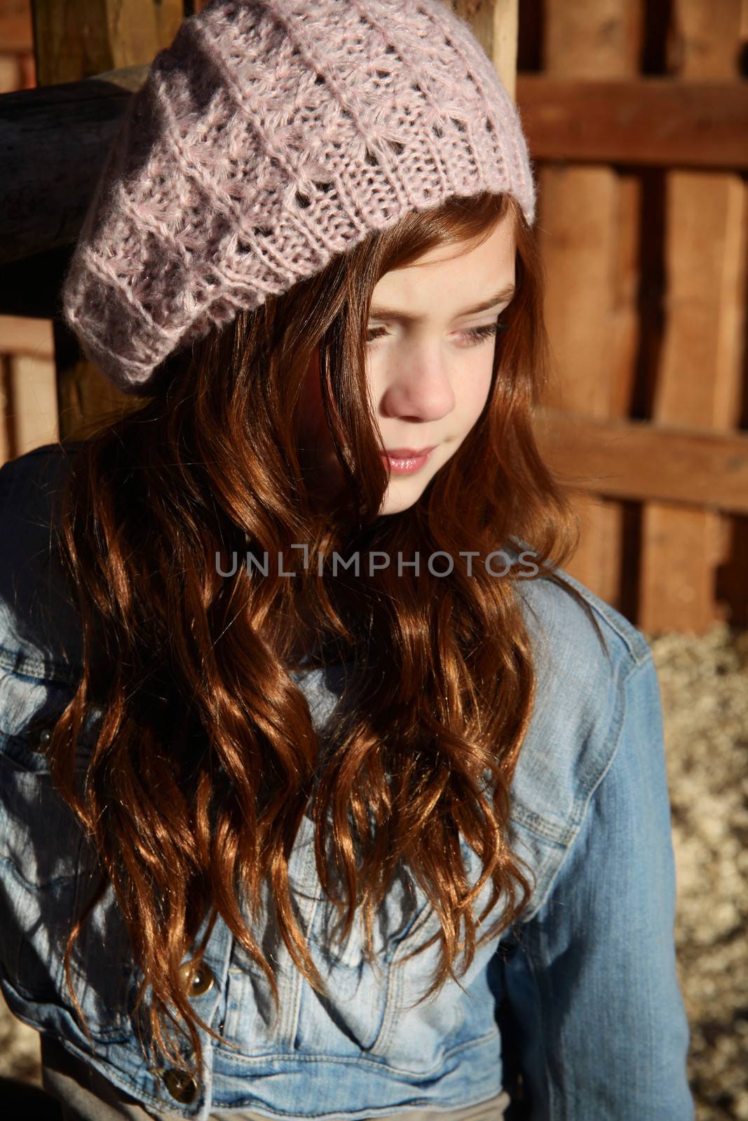 Winter girl leaning against a wooden fence 