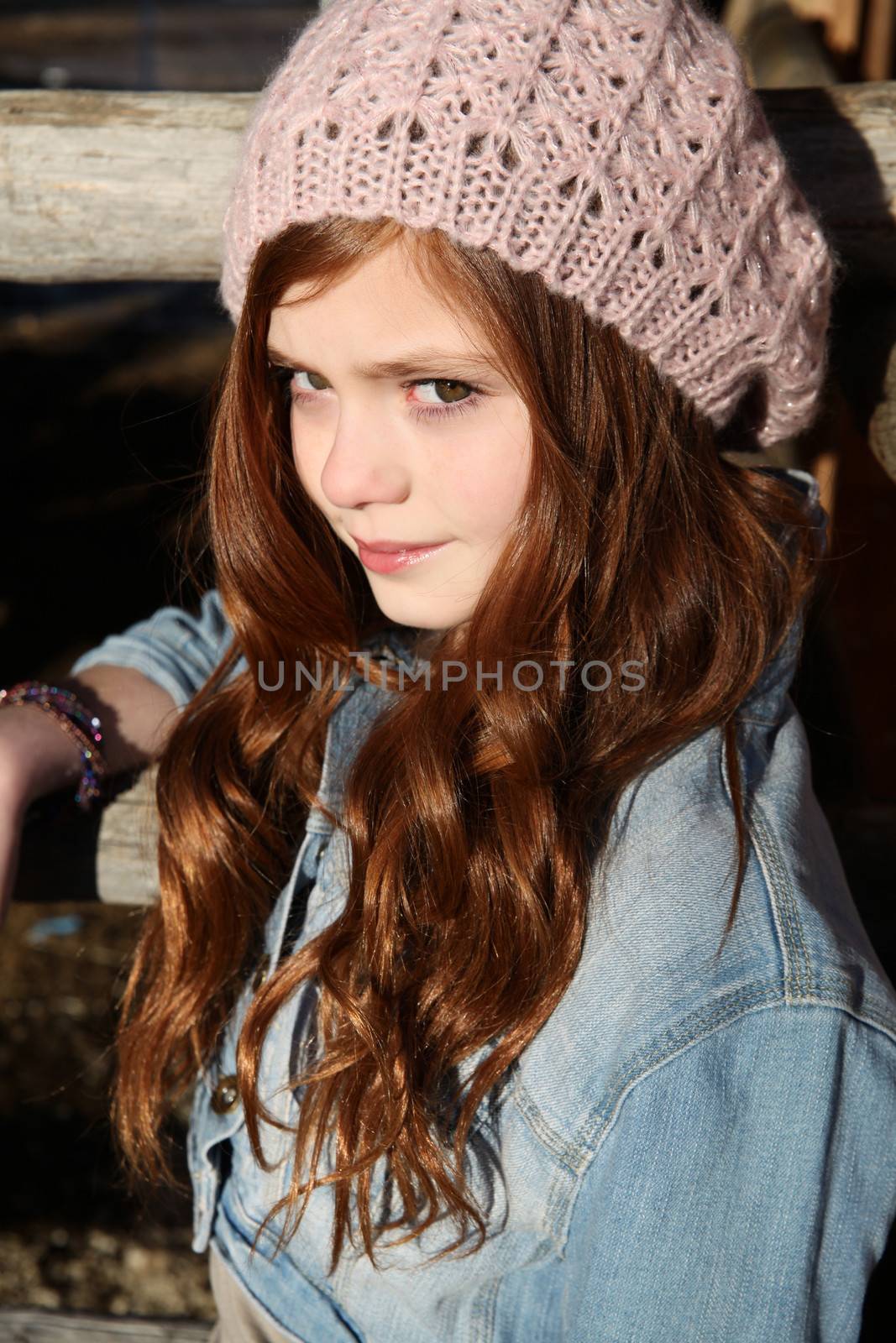 Winter girl leaning against a wooden fence 