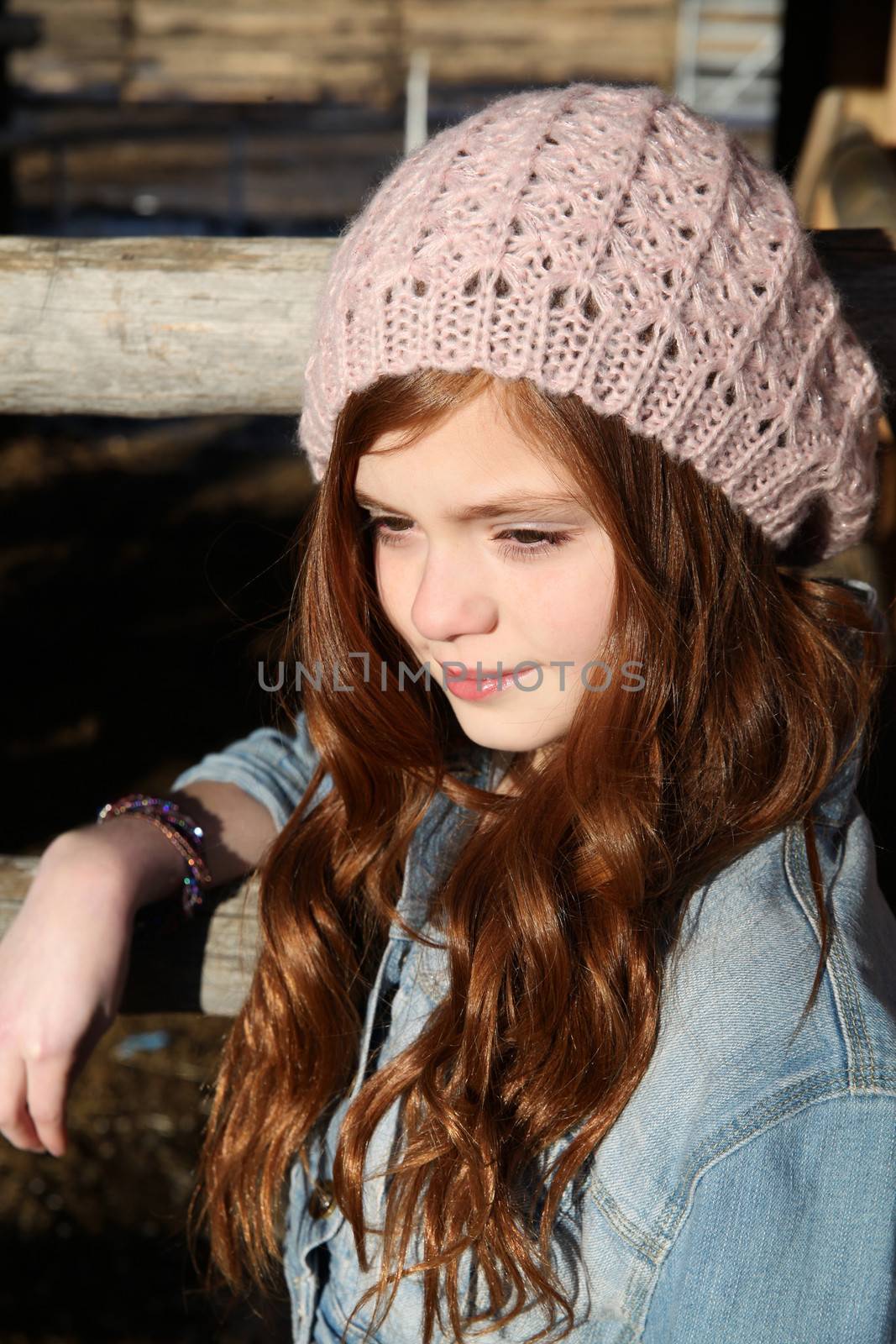 Winter girl leaning against a wooden fence 