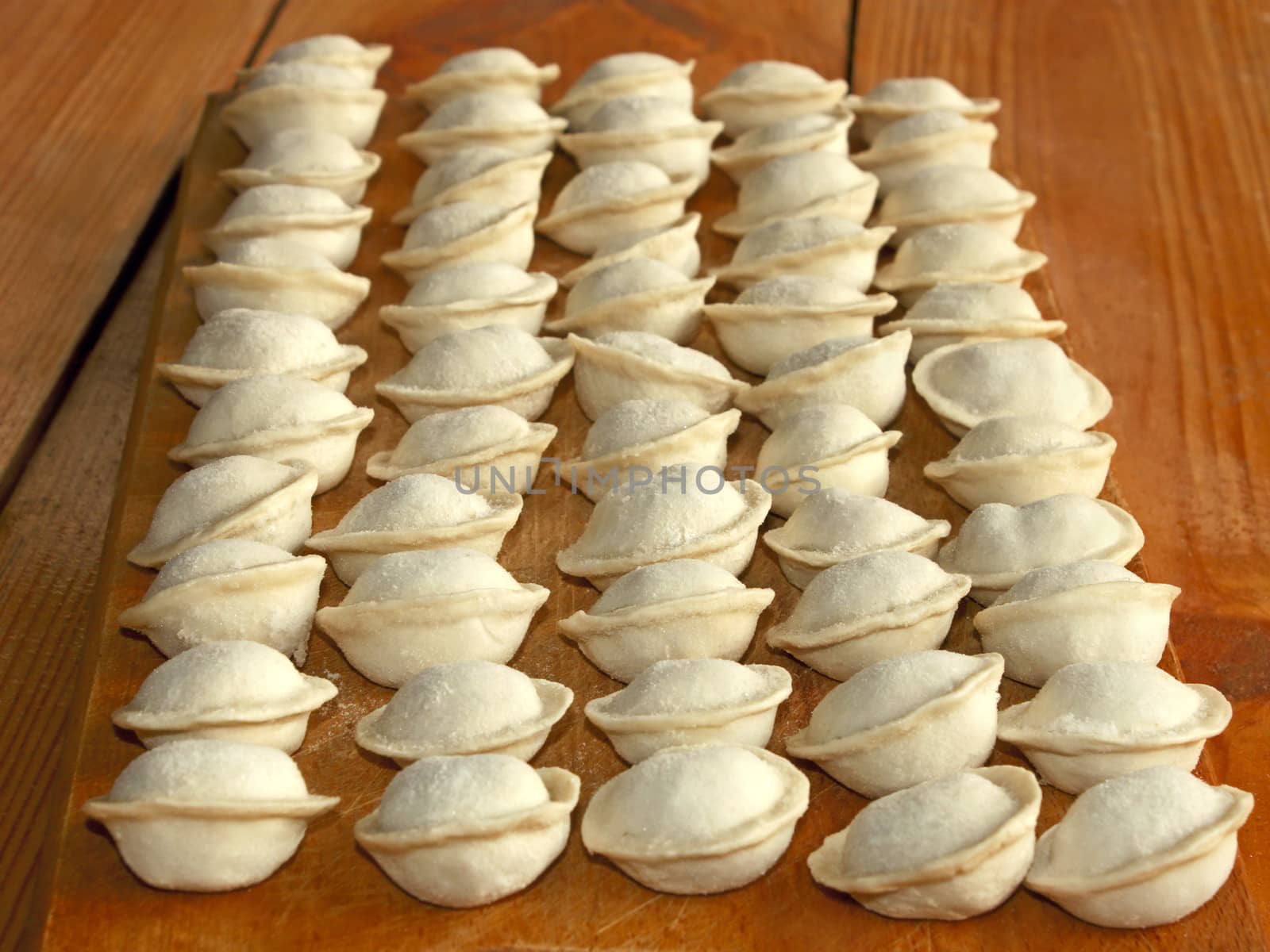 Frozen meat dumplings on the kitchen board. Dumplings or ravioli is a traditional East Slavic kitchen dish or other name as pelmeni