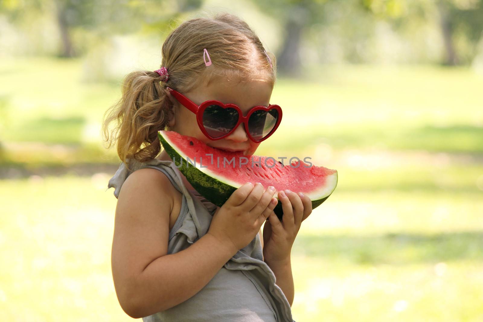 little girl with sunglasses eat watermelon by goce
