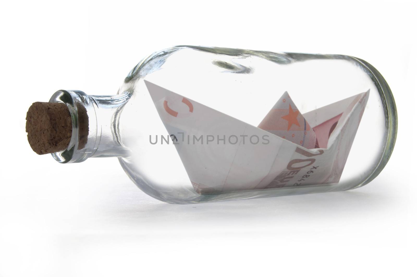 Paper boat made from Euro banknotes inside a message bottle 