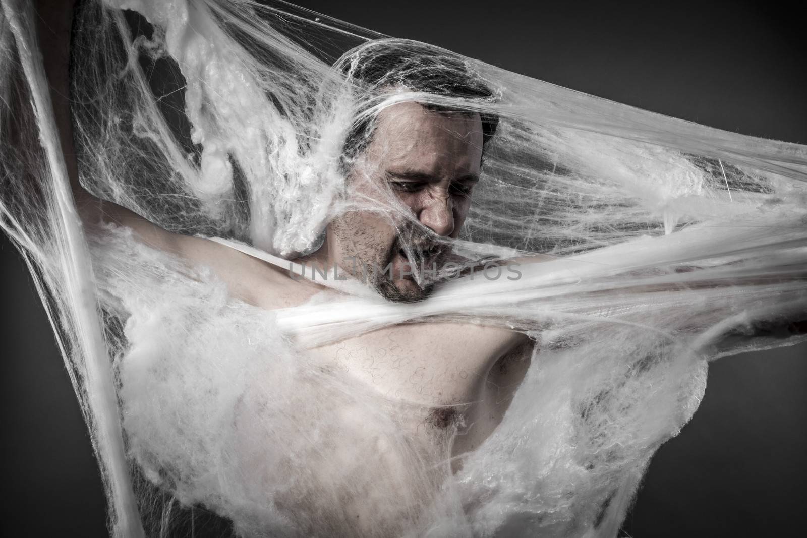 Danger. man tangled in huge white spider web