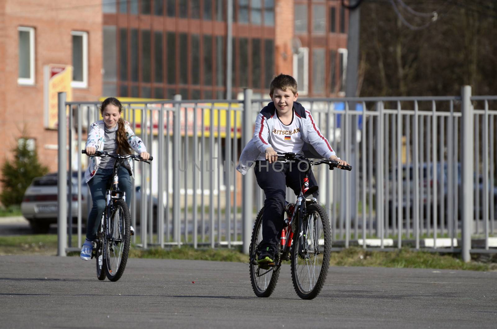 Unknown boy and girl ride bikes through the city on a spring Sunny day