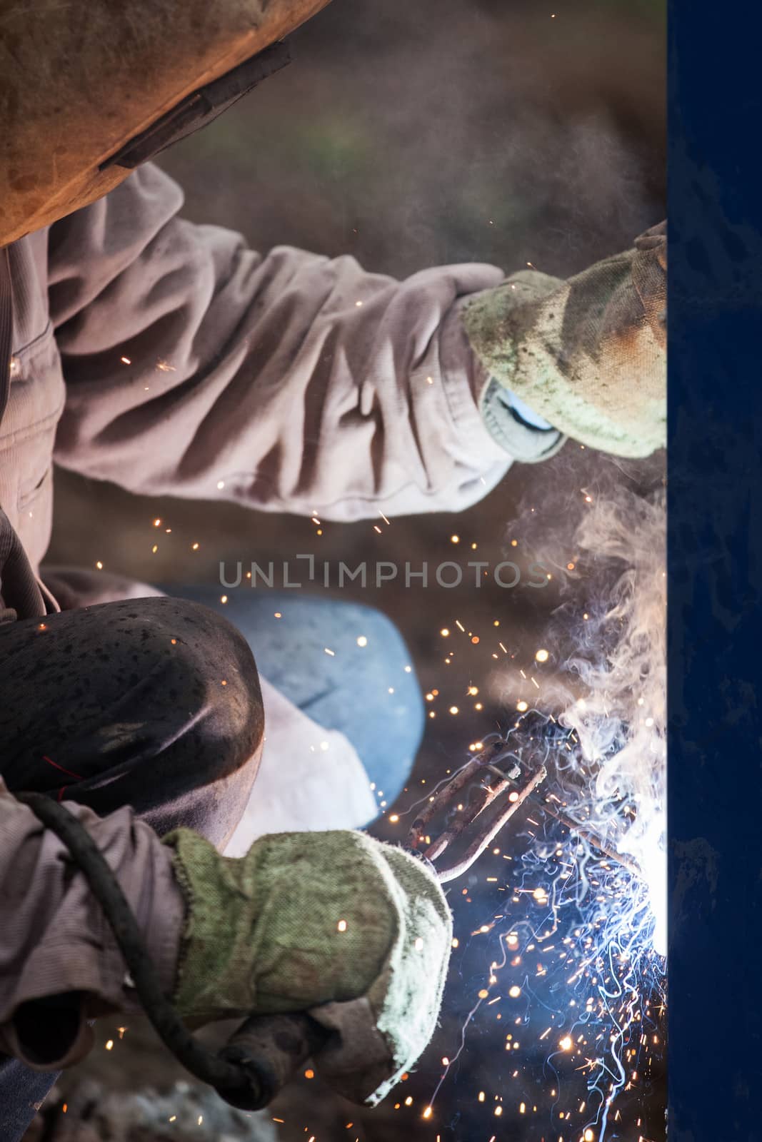 Heavy industry welder worker in protective mask hand holding arc welding torch working on metal construction