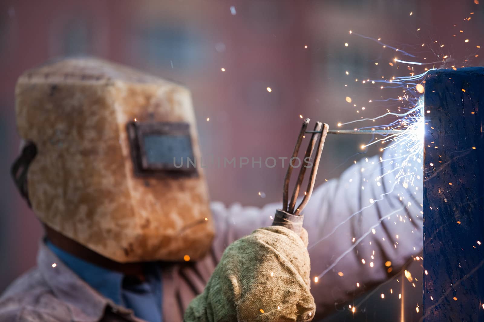 Heavy industry welder worker in protective mask hand holding arc welding torch working on metal construction