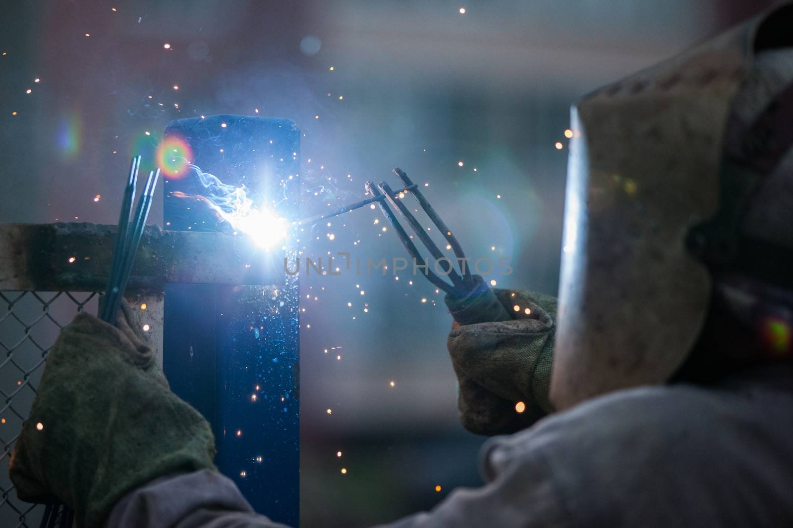 Heavy industry welder worker in protective mask hand holding arc welding torch working on metal construction