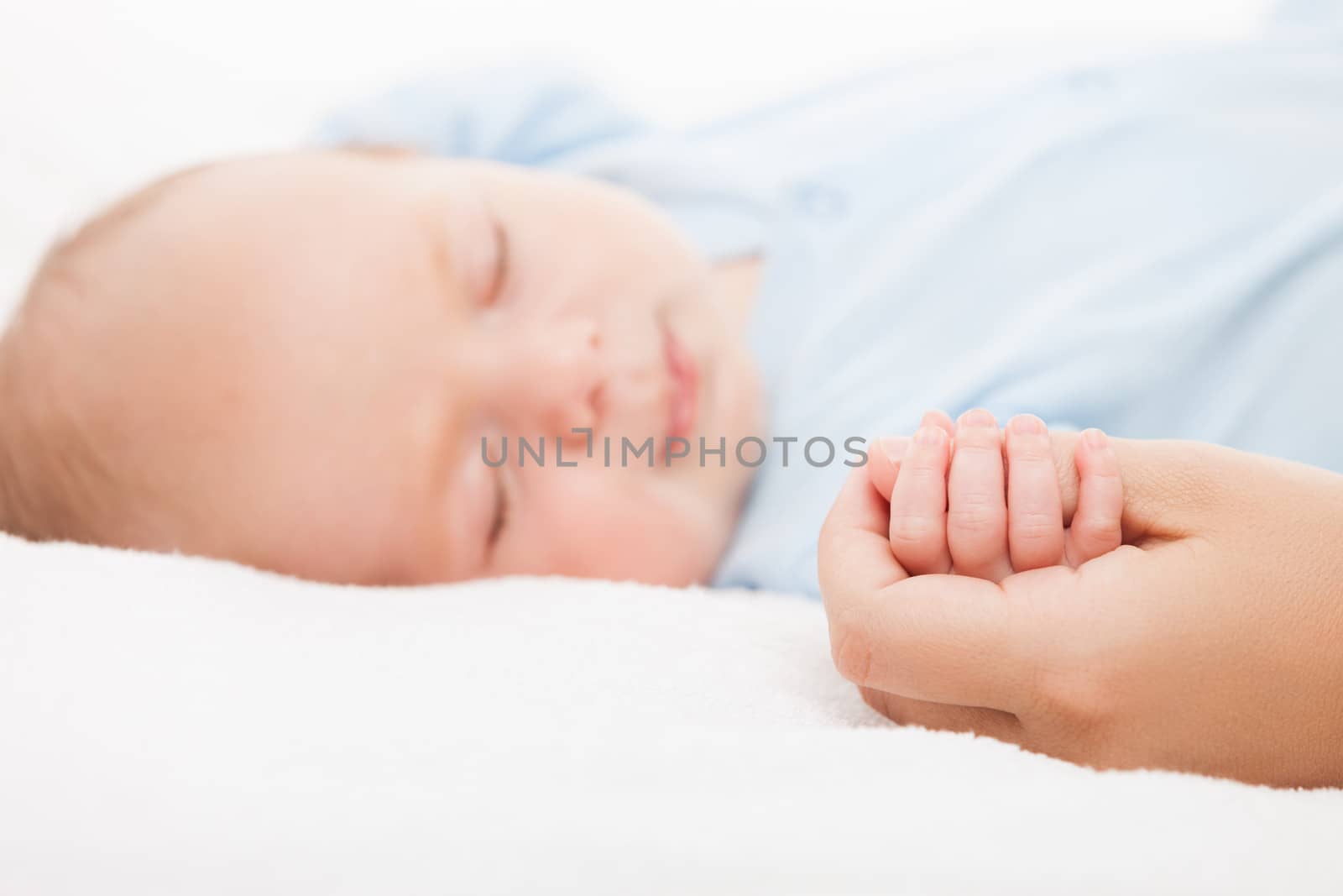 Loving mother hand holding cute sleeping newborn baby child