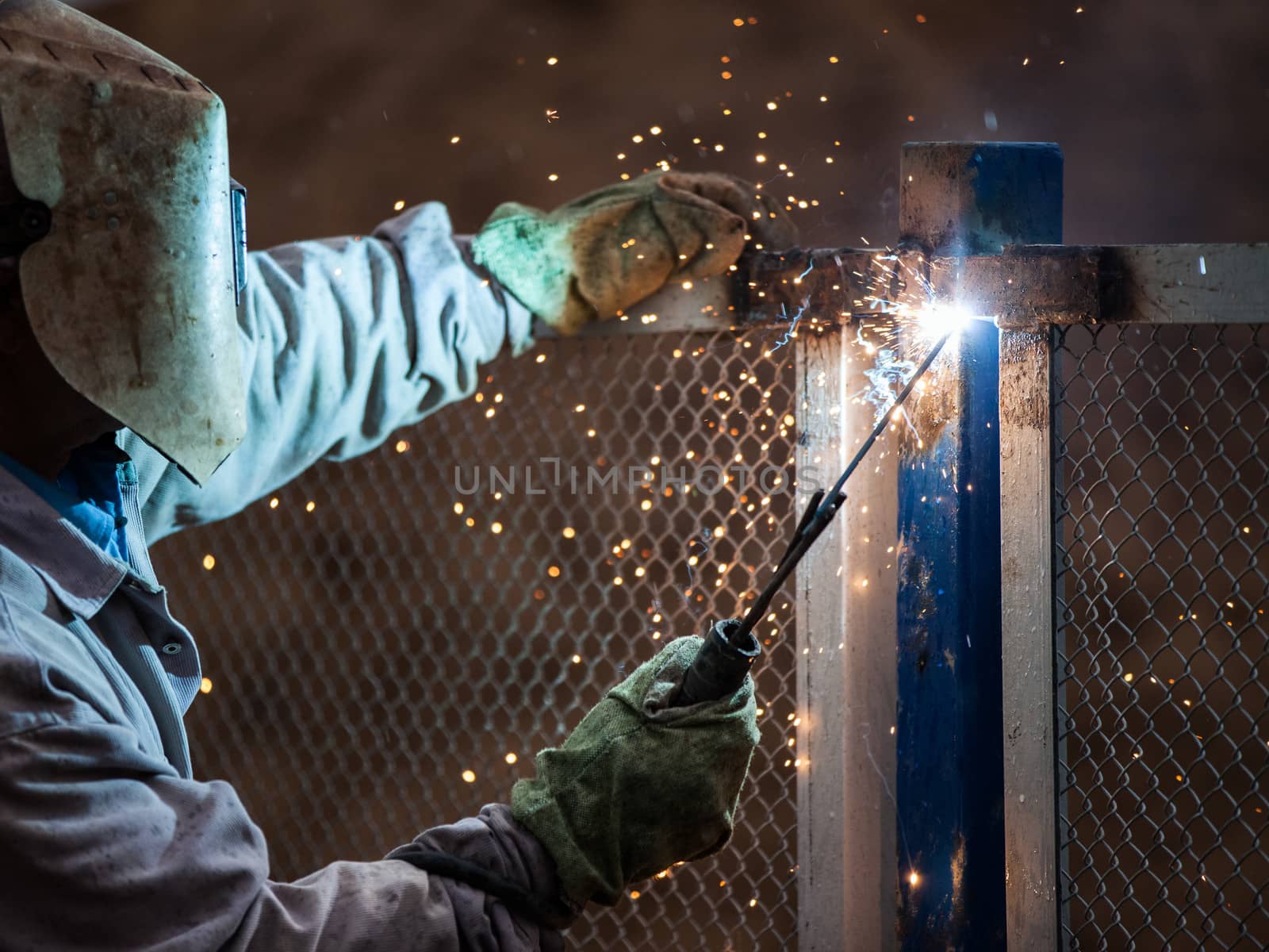 Heavy industry welder worker in protective mask hand holding arc welding torch working on metal construction