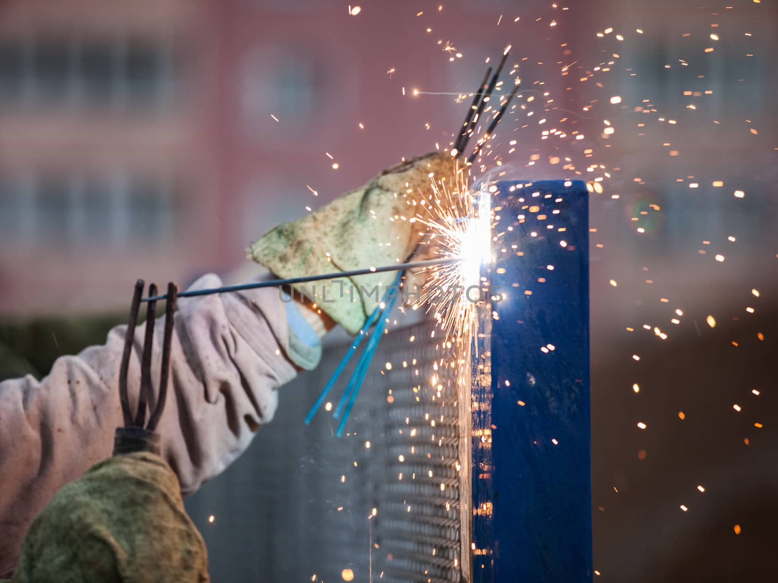 Heavy industry welder worker in protective mask hand holding arc welding torch working on metal construction