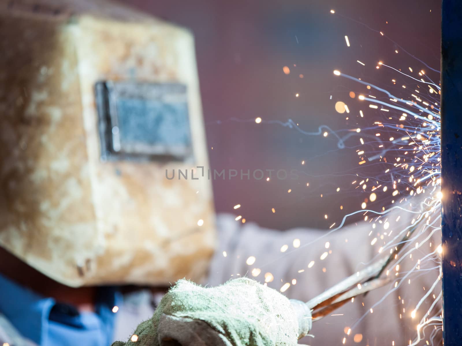 Heavy industry welder worker in protective mask hand holding arc welding torch working on metal construction