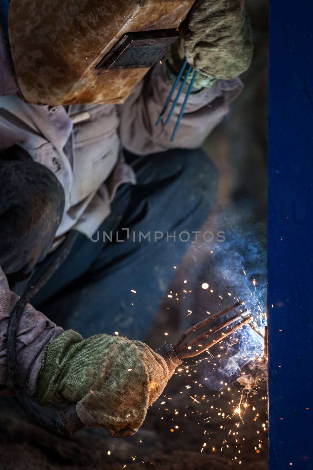 Arc welder worker in protective mask welding metal construction by ia_64