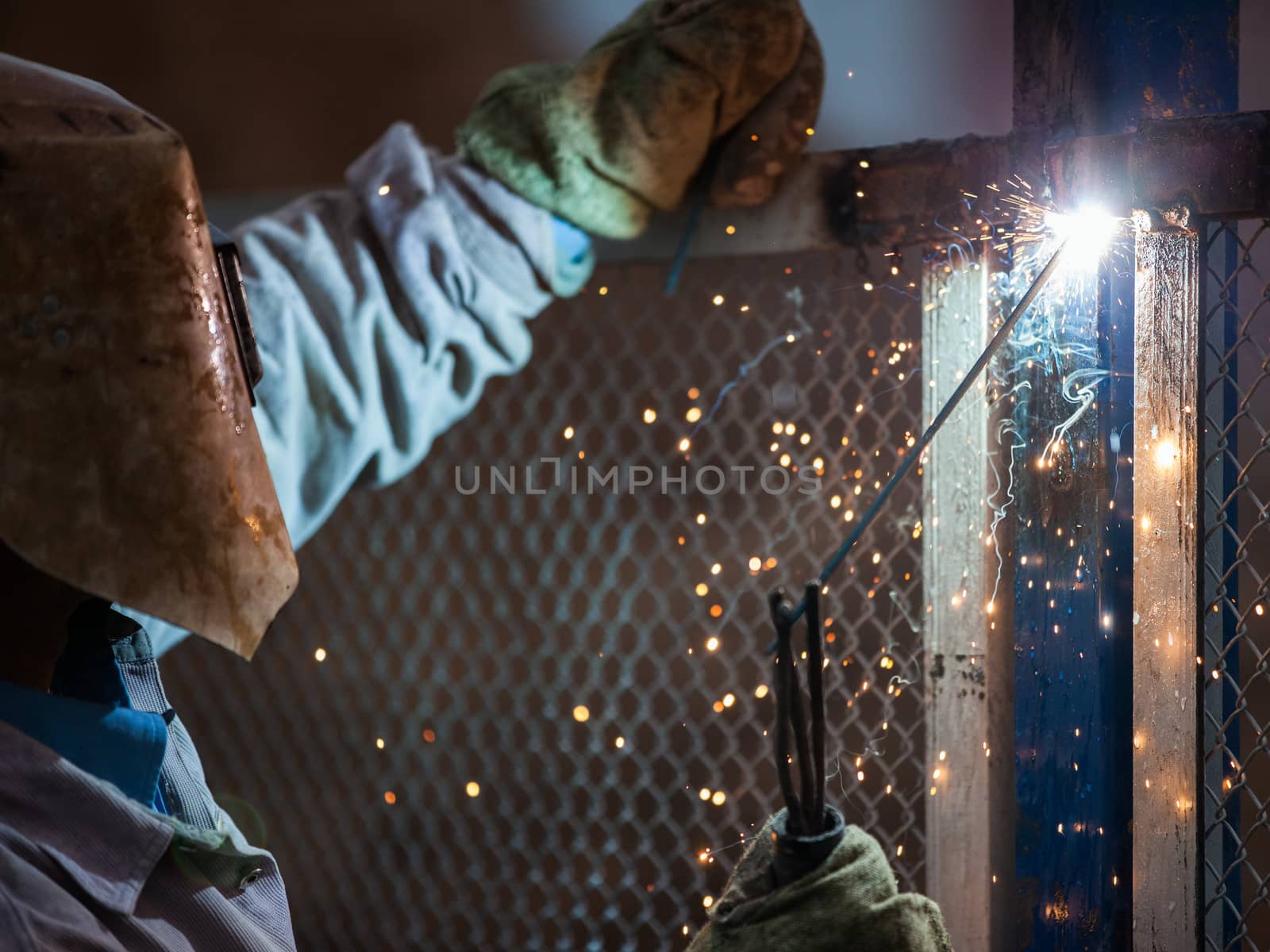 Heavy industry welder worker in protective mask hand holding arc welding torch working on metal construction