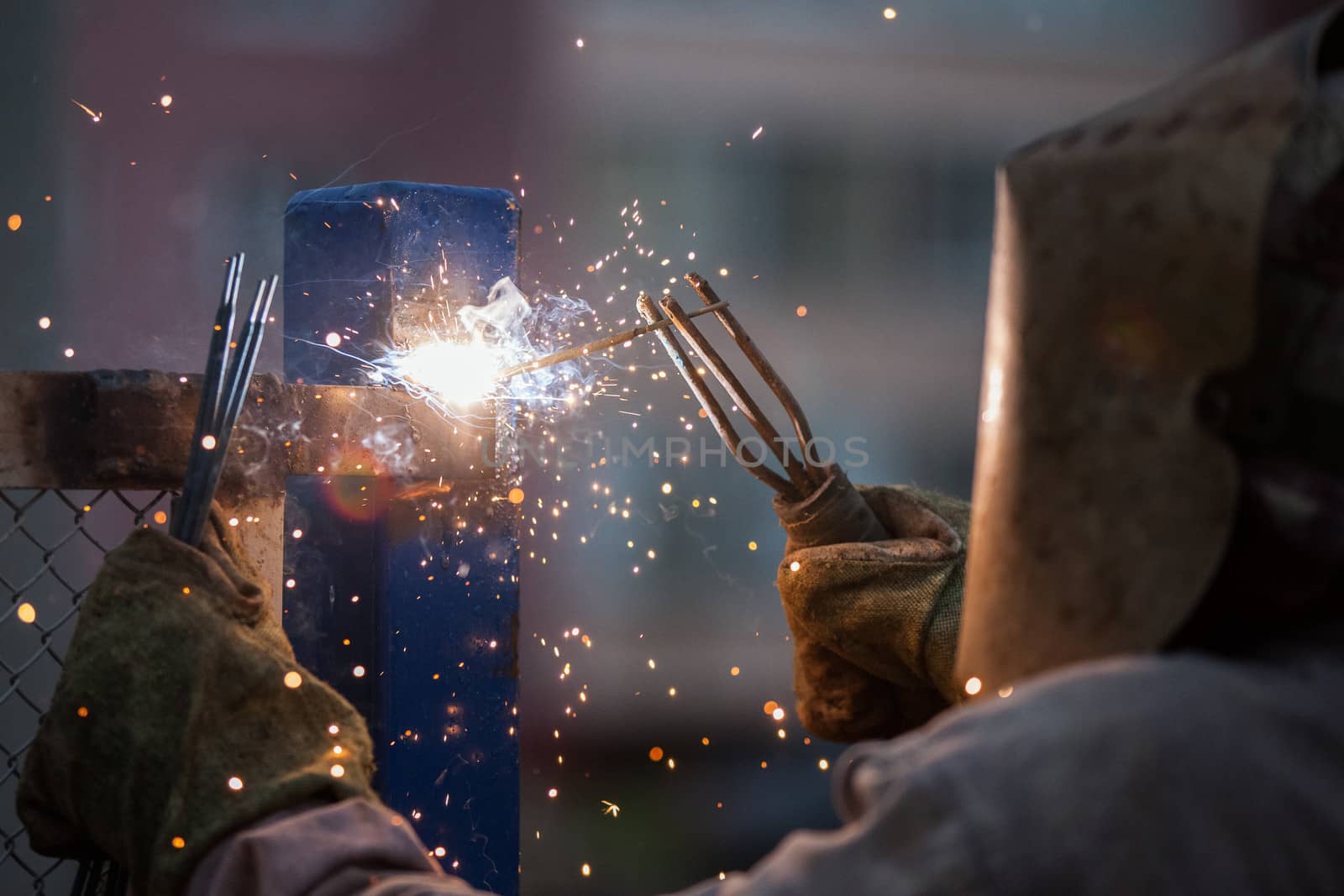 Heavy industry welder worker in protective mask hand holding arc welding torch working on metal construction