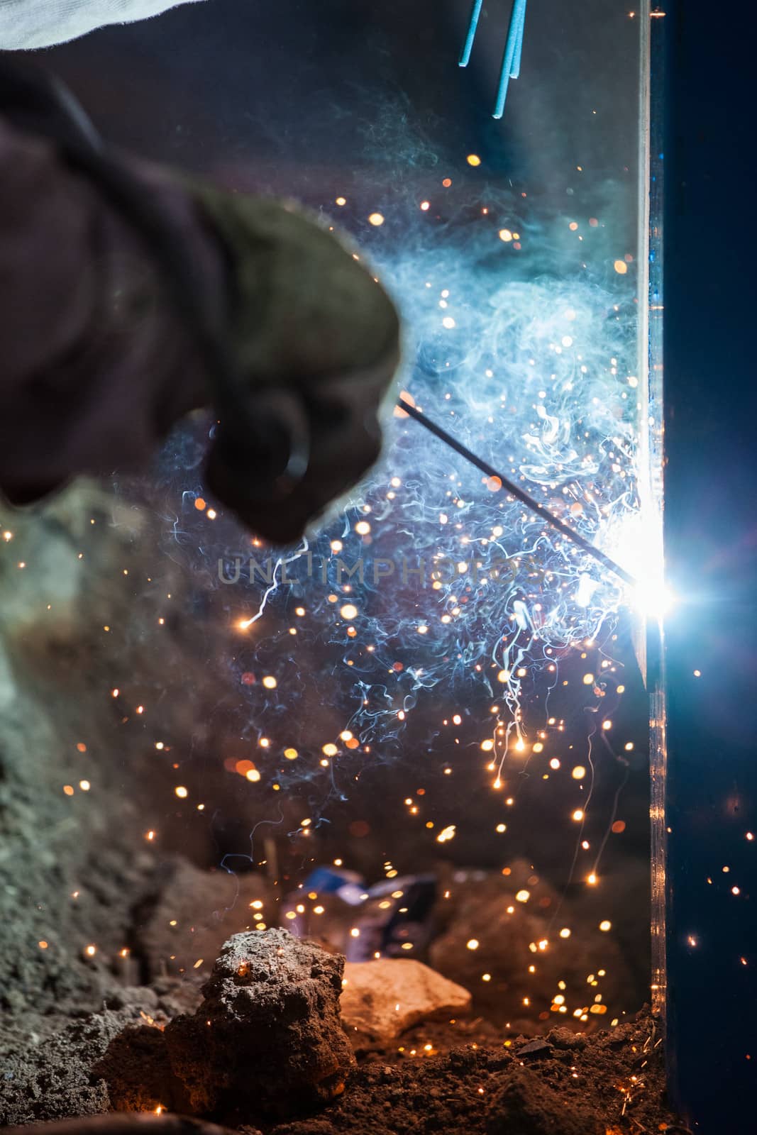 Heavy industry welder worker in protective mask hand holding arc welding torch working on metal construction