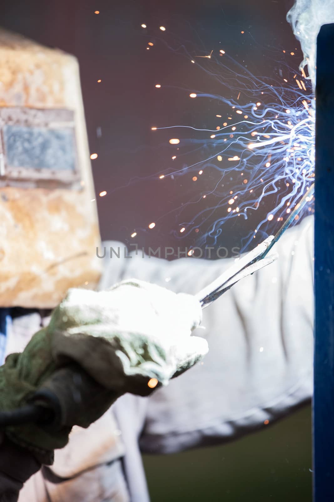 Arc welder worker in protective mask welding metal construction by ia_64