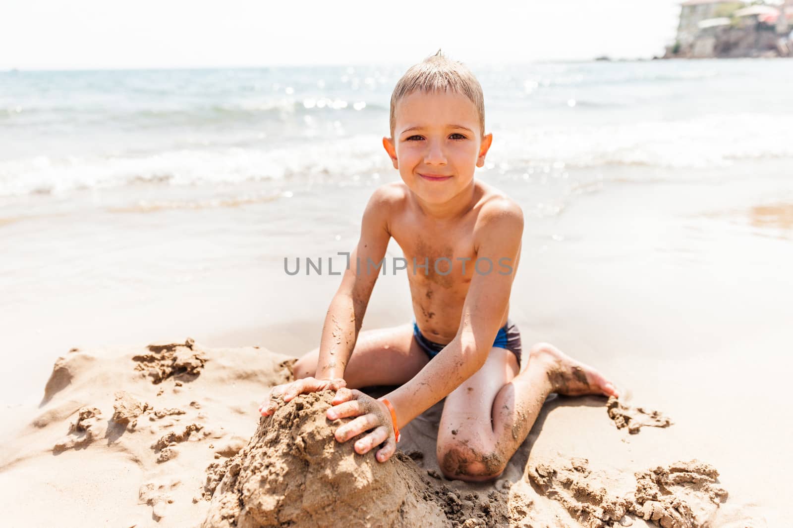 Summer vacations - little smiling child boy playing on blue sea sand beach