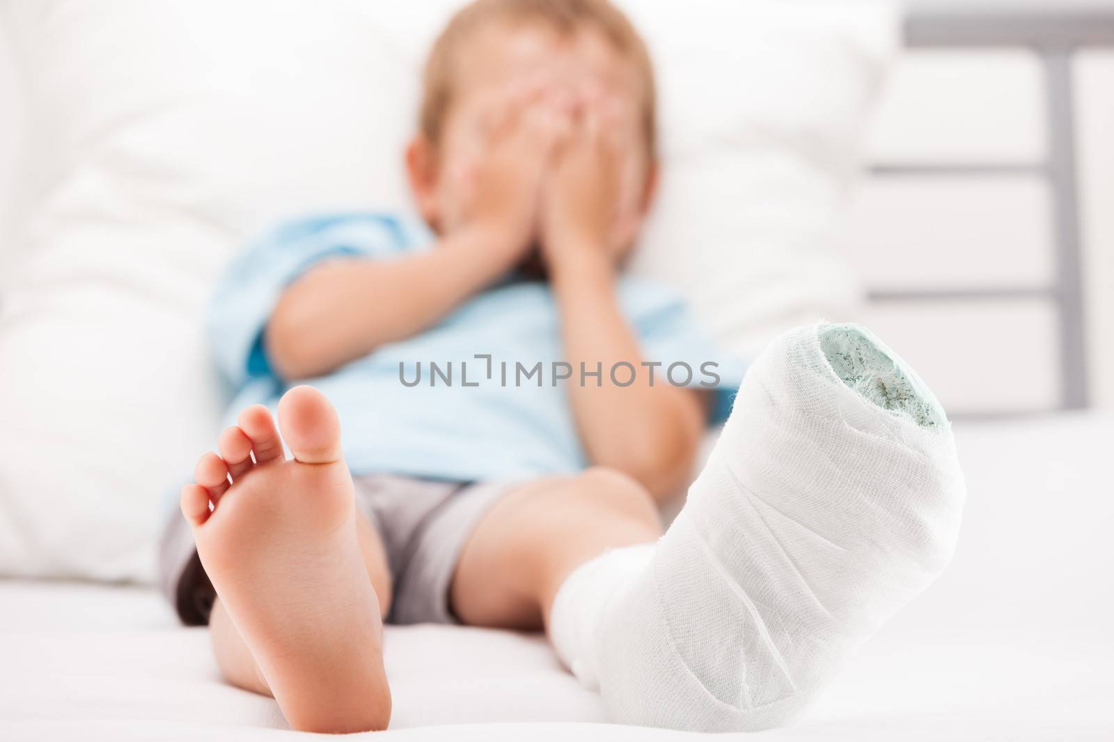 Little child boy with plaster bandage on leg heel fracture or br by ia_64