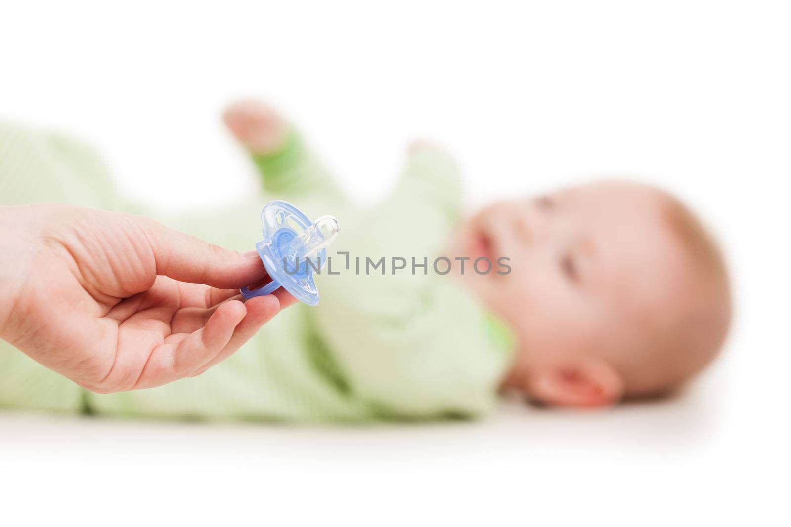Mother hand giving plastic soother pacifier to little cute sleeping newborn baby child white isolated