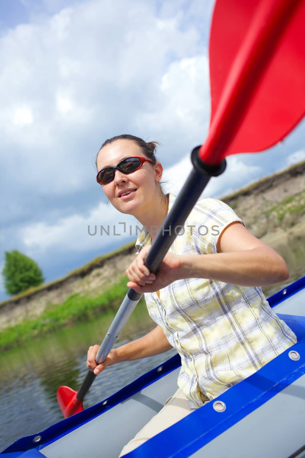 Happy woman paddling a kayak on the river, enjoying a lovely summer day