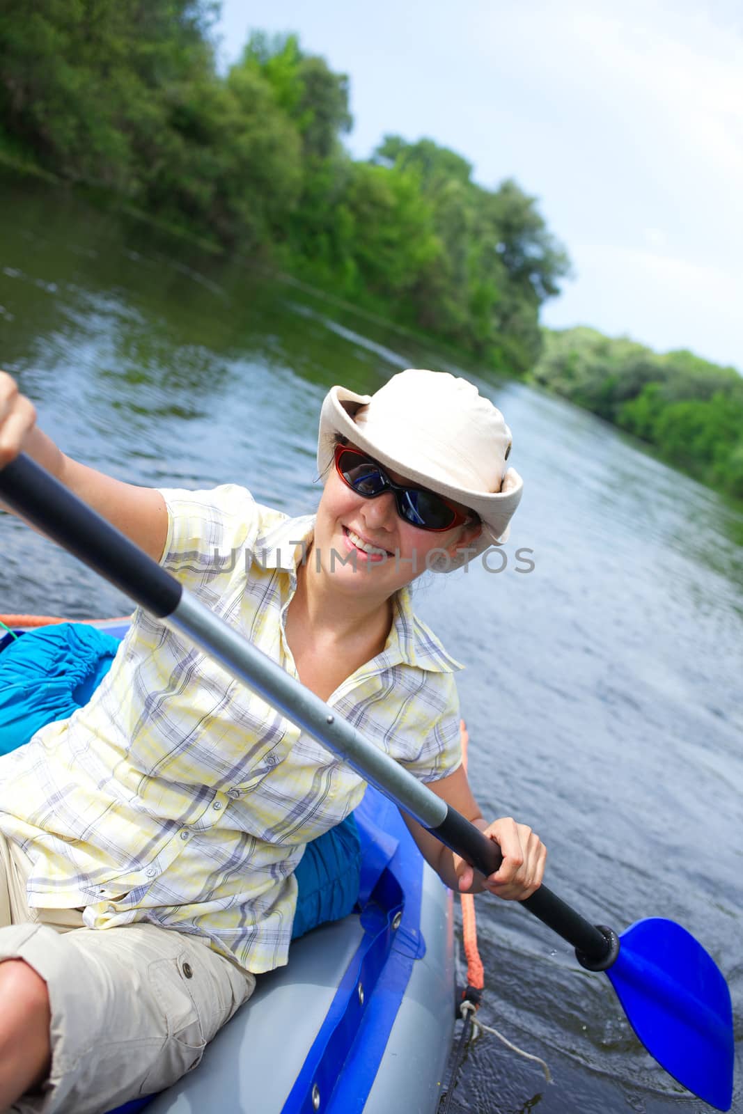 Happy woman paddling a kayak on the river, enjoying a lovely summer day