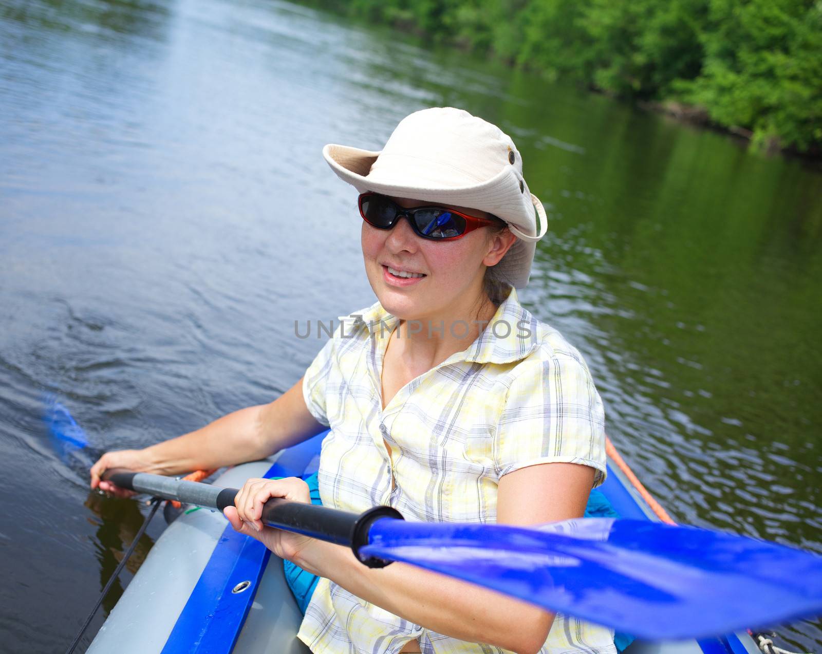 Happy woman paddling a kayak on the river, enjoying a lovely summer day