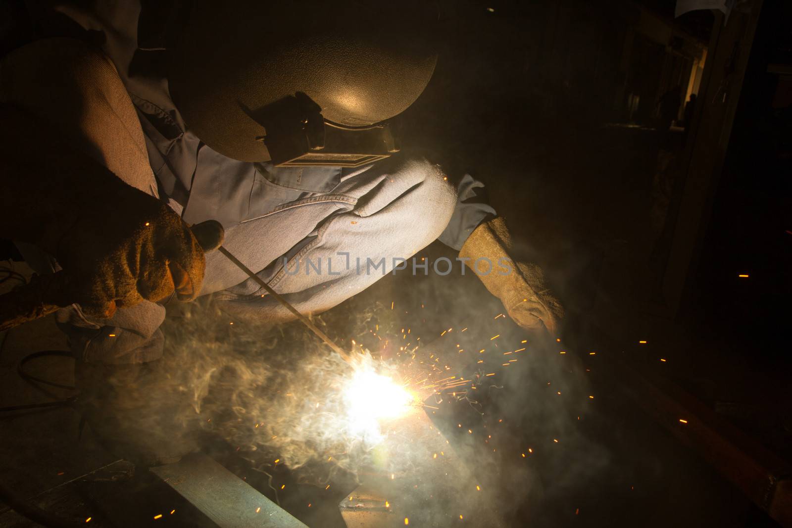 Welder with sparks arcing, industrial background