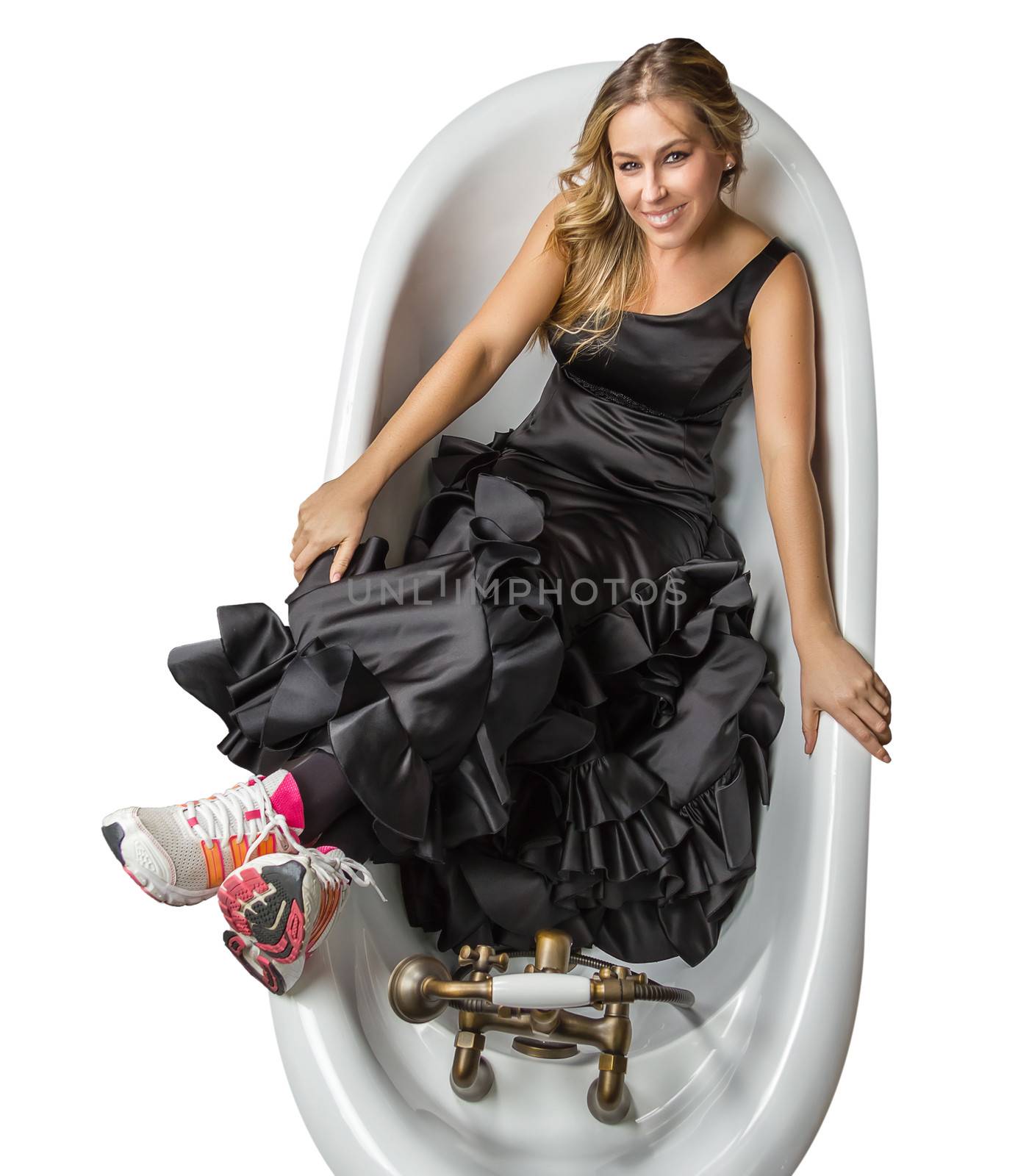 Portrait of beautiful fashion girl with black spanish flamenco dress and running shoes posing in a vintage bathtub on white background