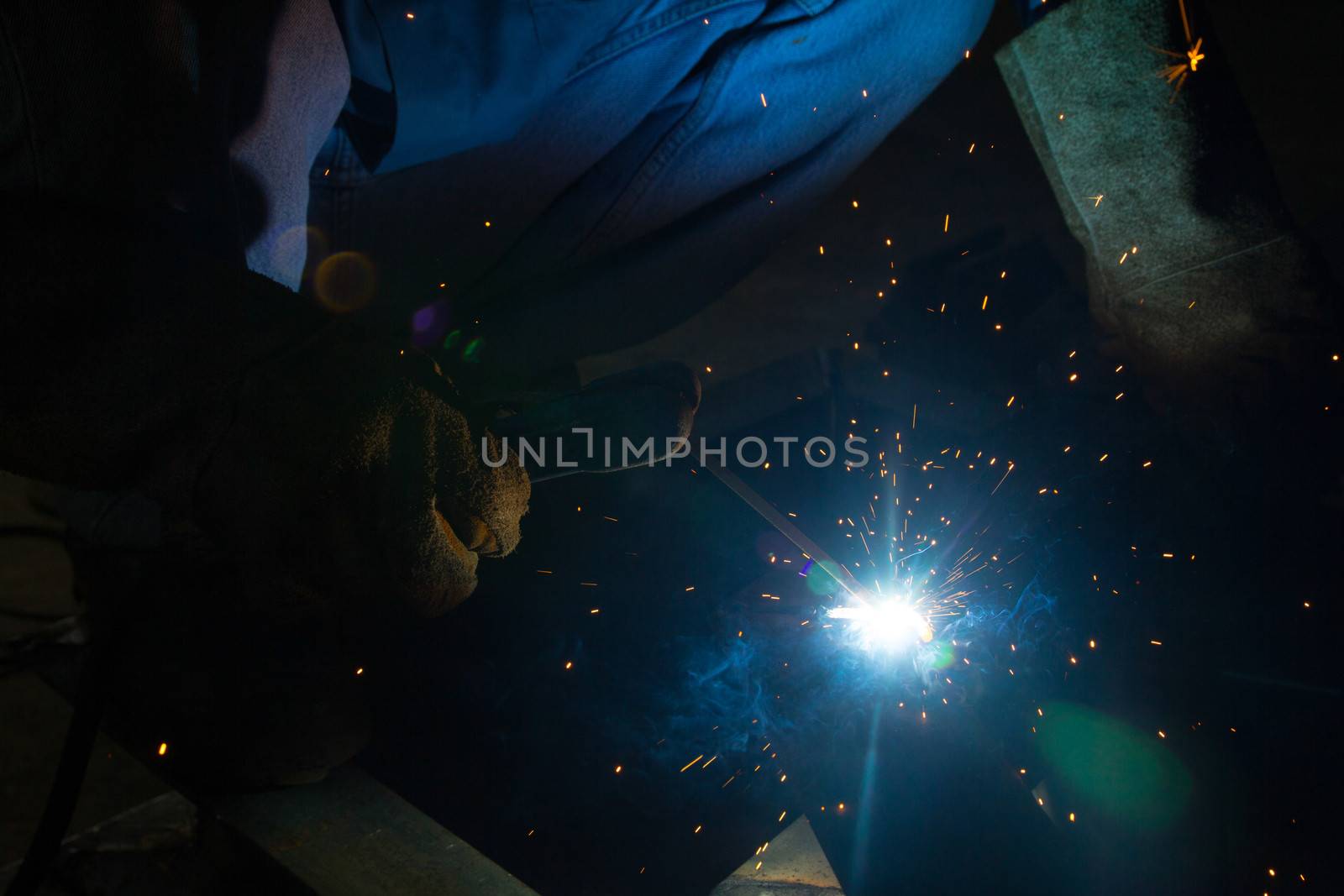 Welder with sparks arcing, industrial background