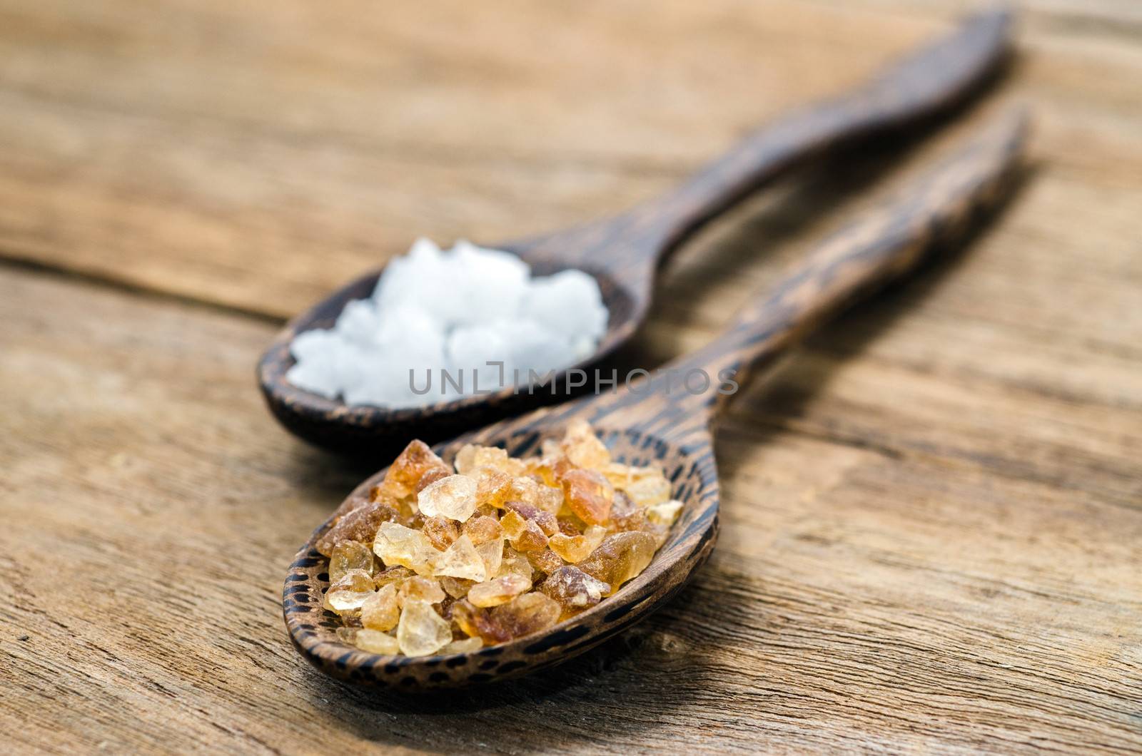 two wood spoon with sal  and crystalline sugar on wood table