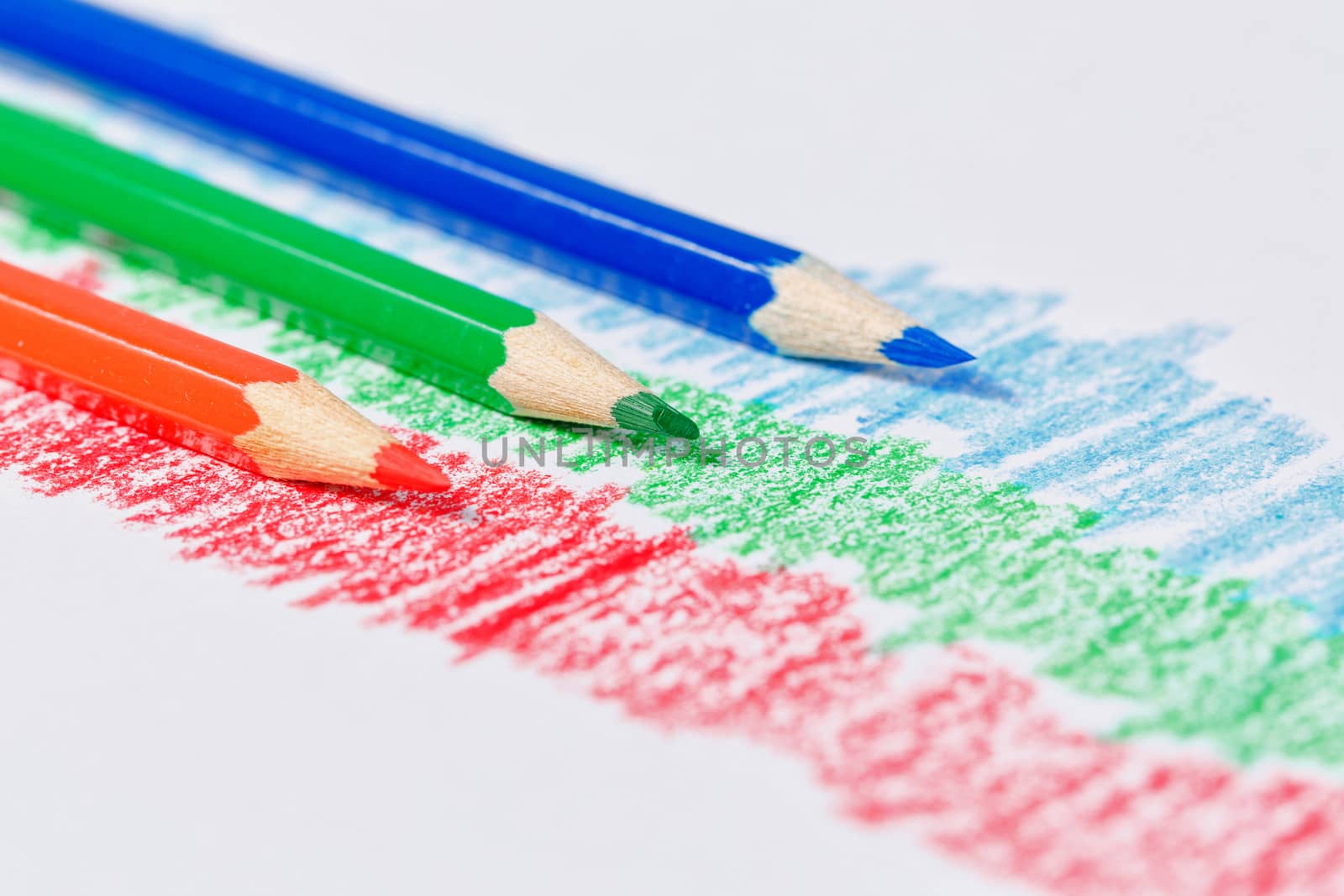 RGB pencils and abstract lines of red, green and blue color on textured paper