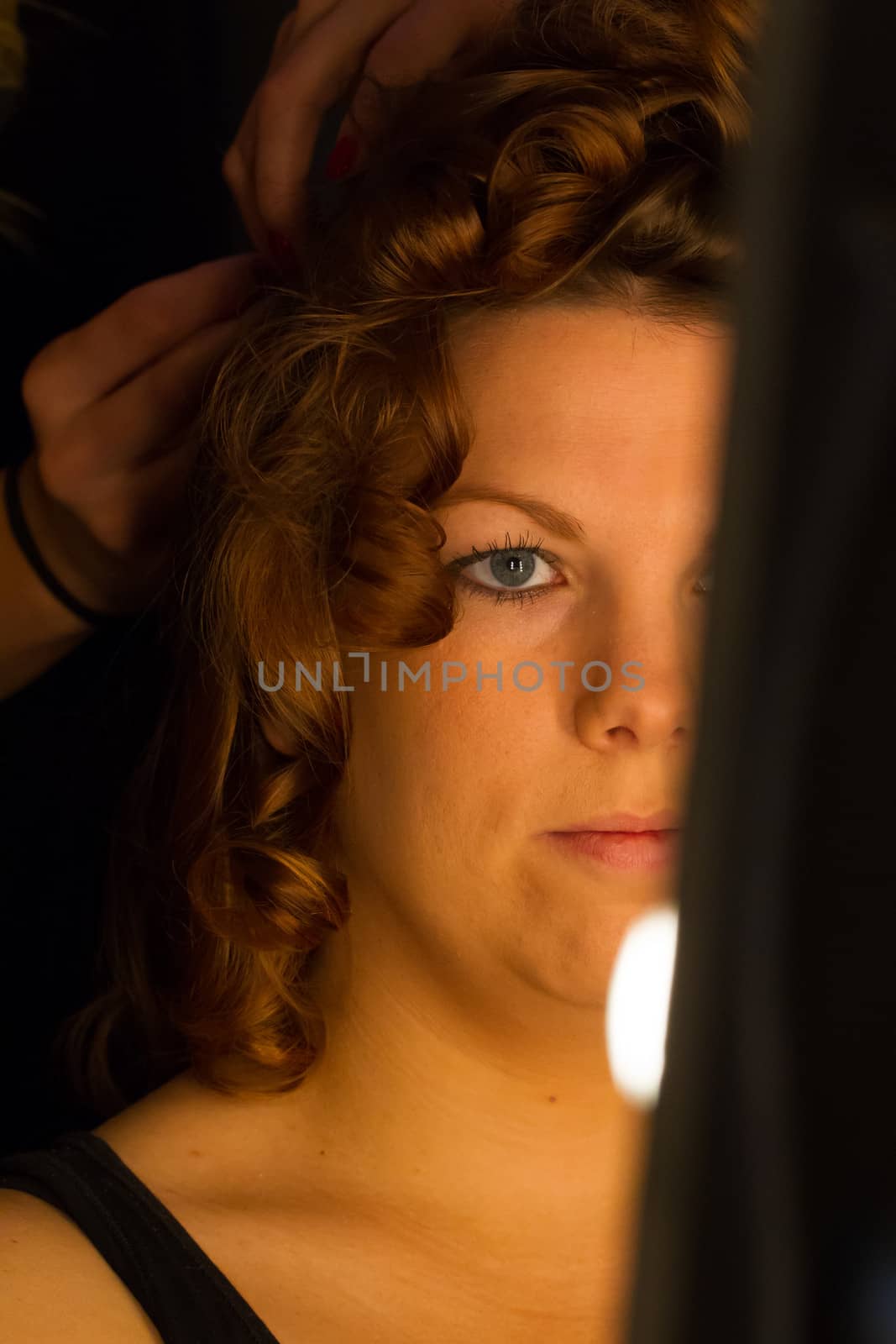 Woman applying make up for a bride in her wedding day near mirro by michaklootwijk