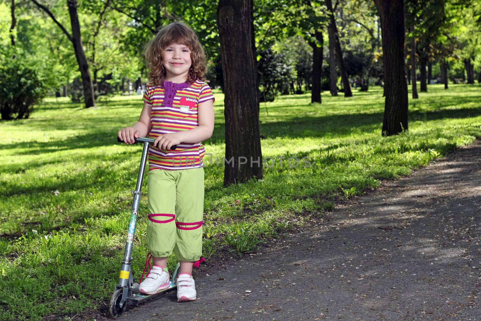 beautiful little girl with scooter in park