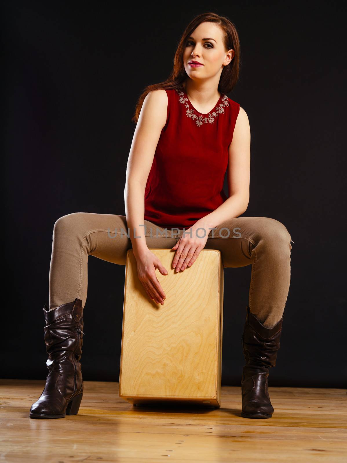 Photo of a beautiful young woman playing a Cajon percussion instrument.
