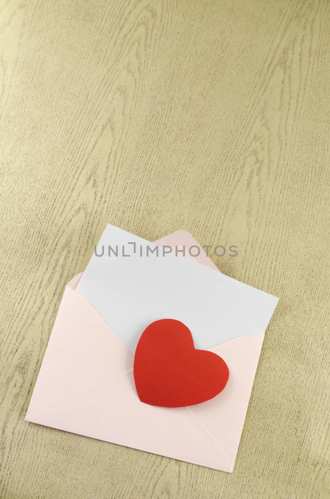 red heart with pink envelope on wooden background