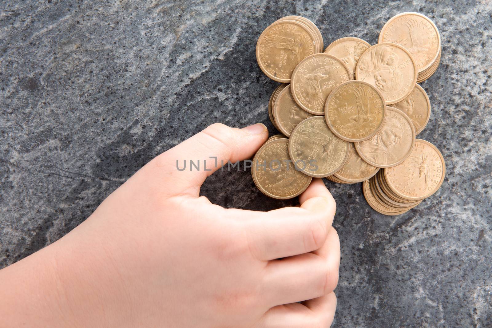 Hand of a man stacking American dollar coins arranging them in a neat symmetrical configuration on a stone countertop conceptual of saving, financial planning and budgeting, overhead view