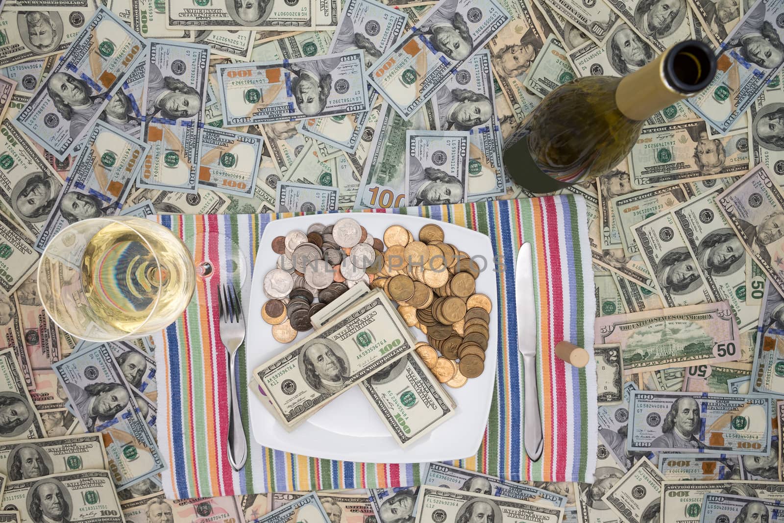 Conceptual financial image of a plate of money with cutlery flanked by a bottle and glass of champagne on a background of 100 dollar bills depicting eating money through greed and extravagance