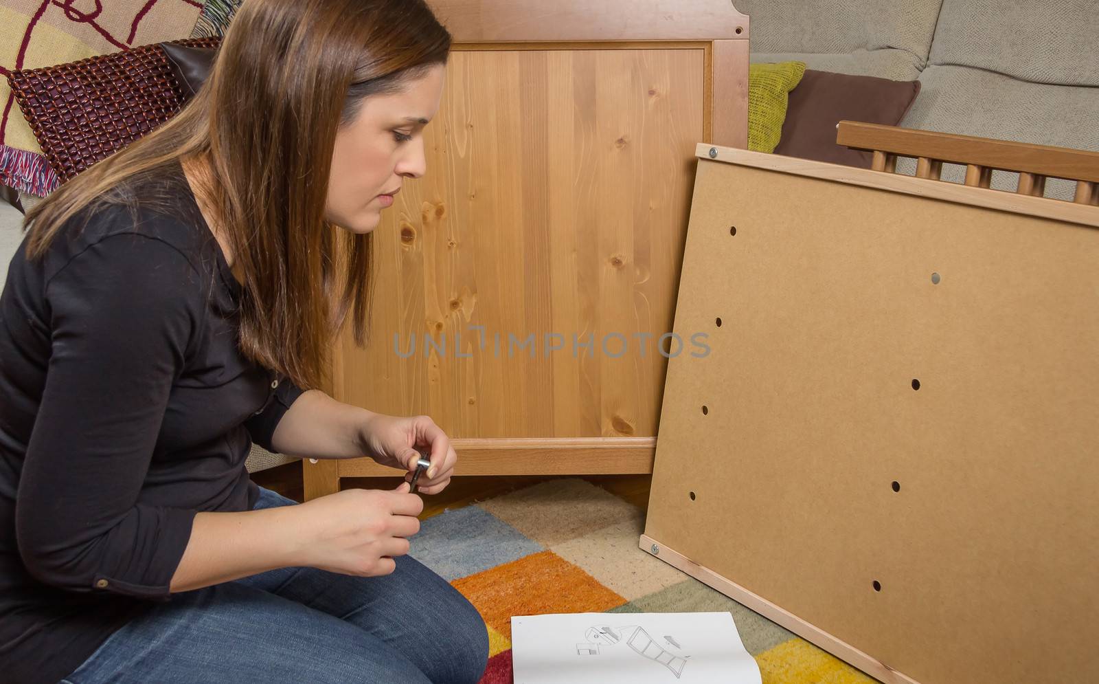 Girl reading instructions to assemble furniture by doble.d