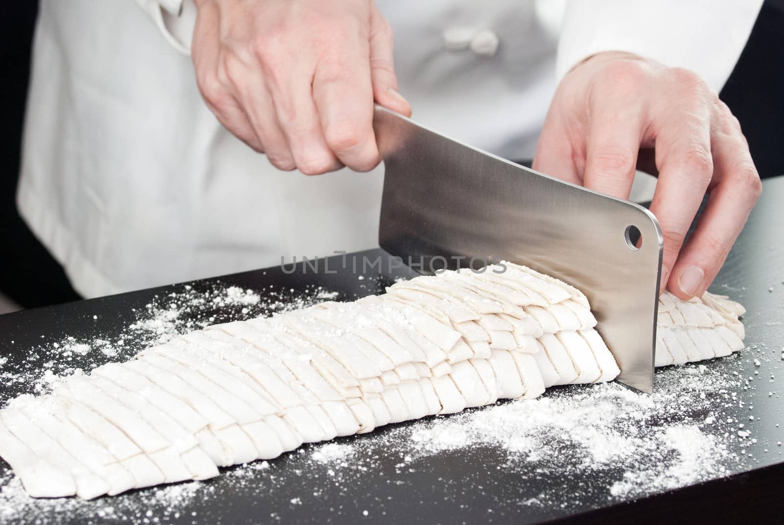 Close-up of a Chef cutting fresh pasta, side view.