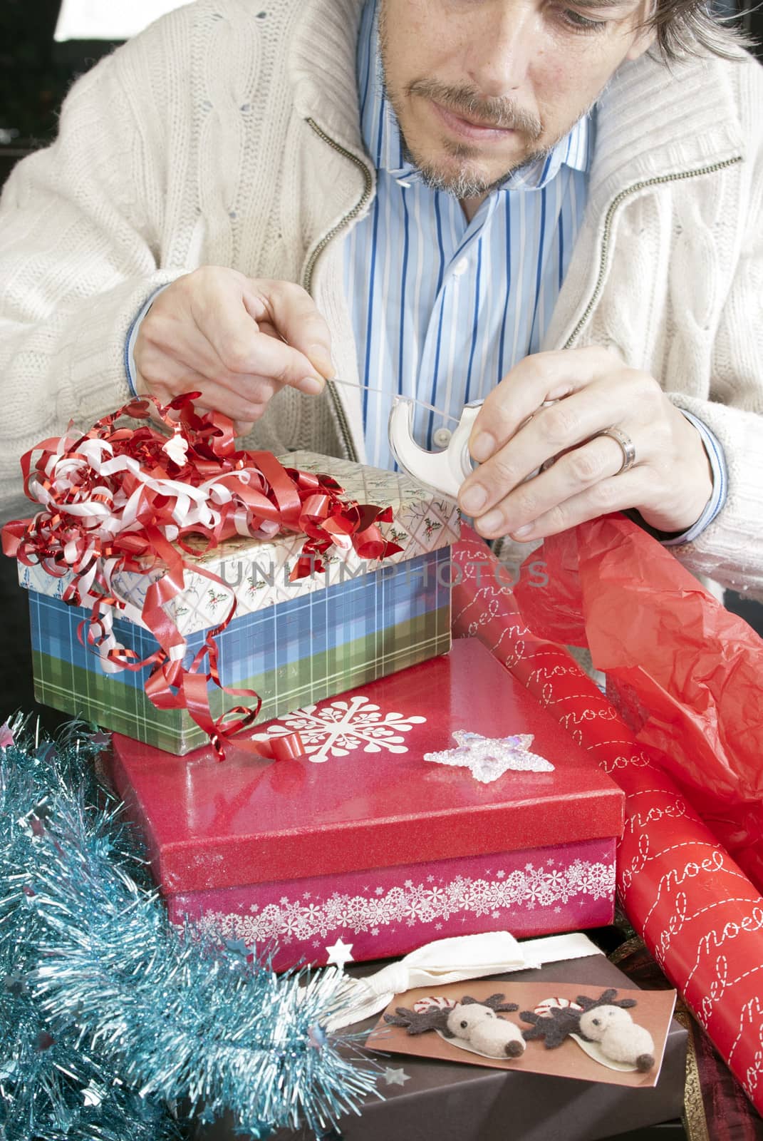 Close-up of a man concentrating on wrapping christmas gifts.