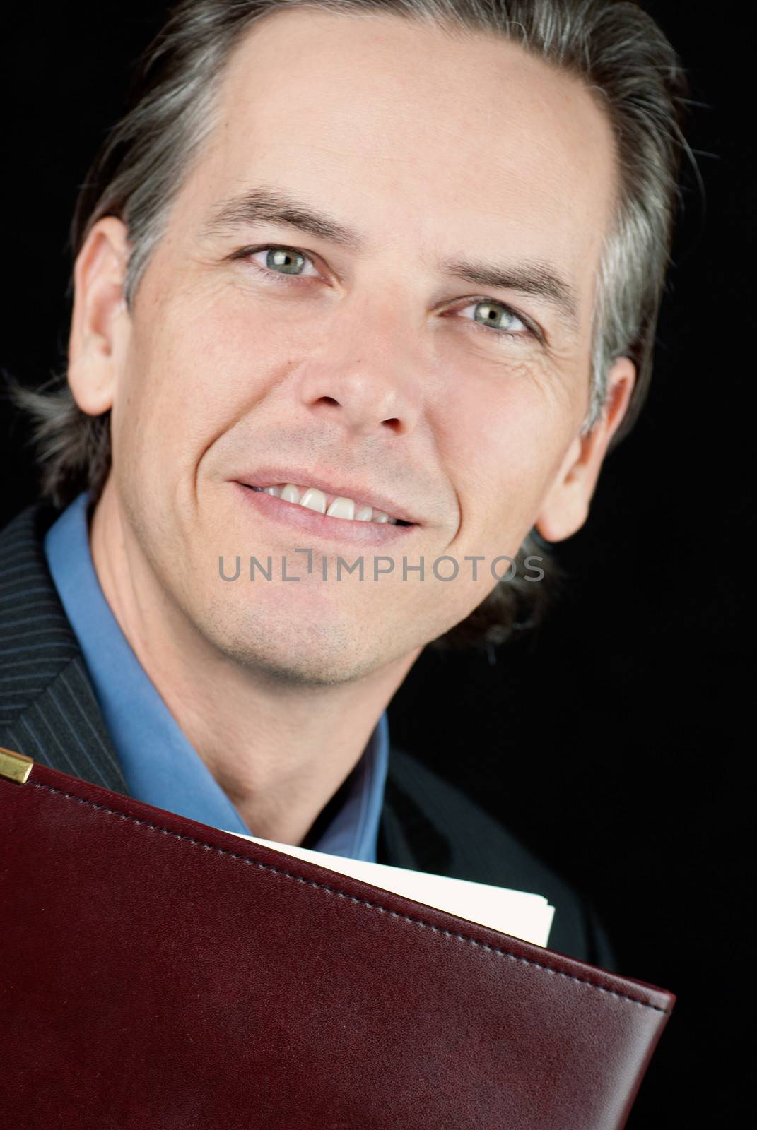 Close-up of a confident businessman holding a lether folder.