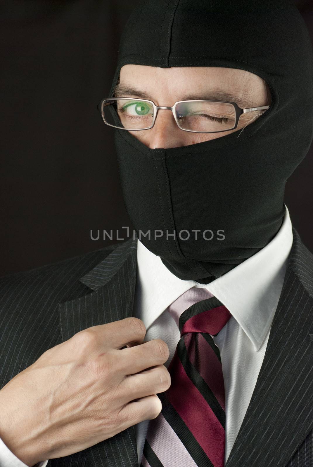 Close-up of a businessman wearing a balaclava winking to camera