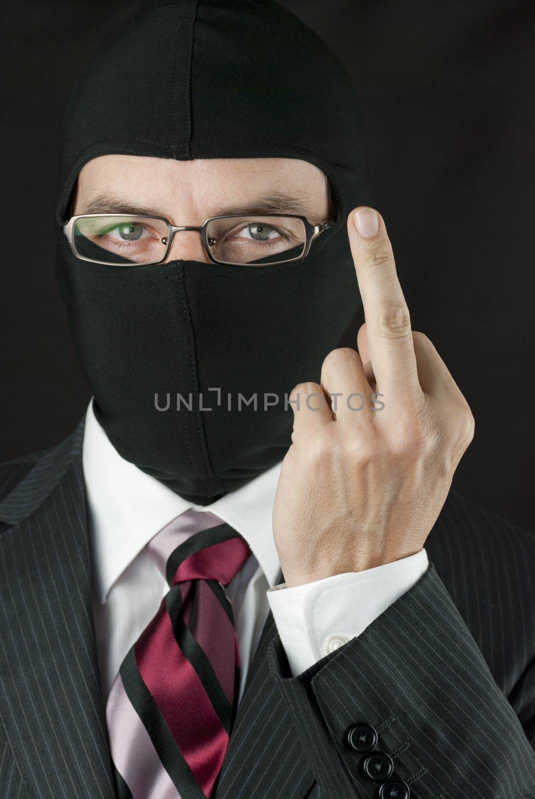 Close-up of a businessman wearing a balaclava giving the finger