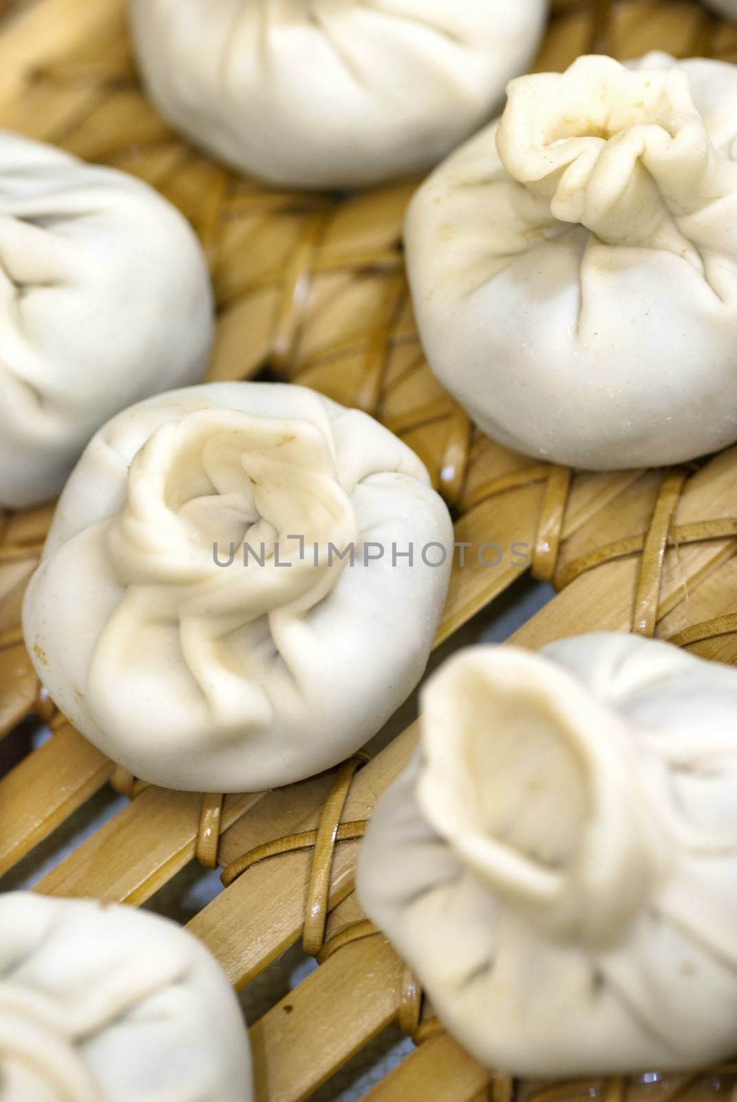 Close-up of a bamboo steamer filled with Tibetan style meatball and vegetarian momos ready to be steamed.