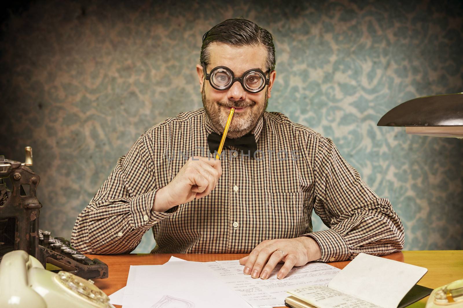 Pensive office employee with a pencil in his mouth looking up in by digicomphoto