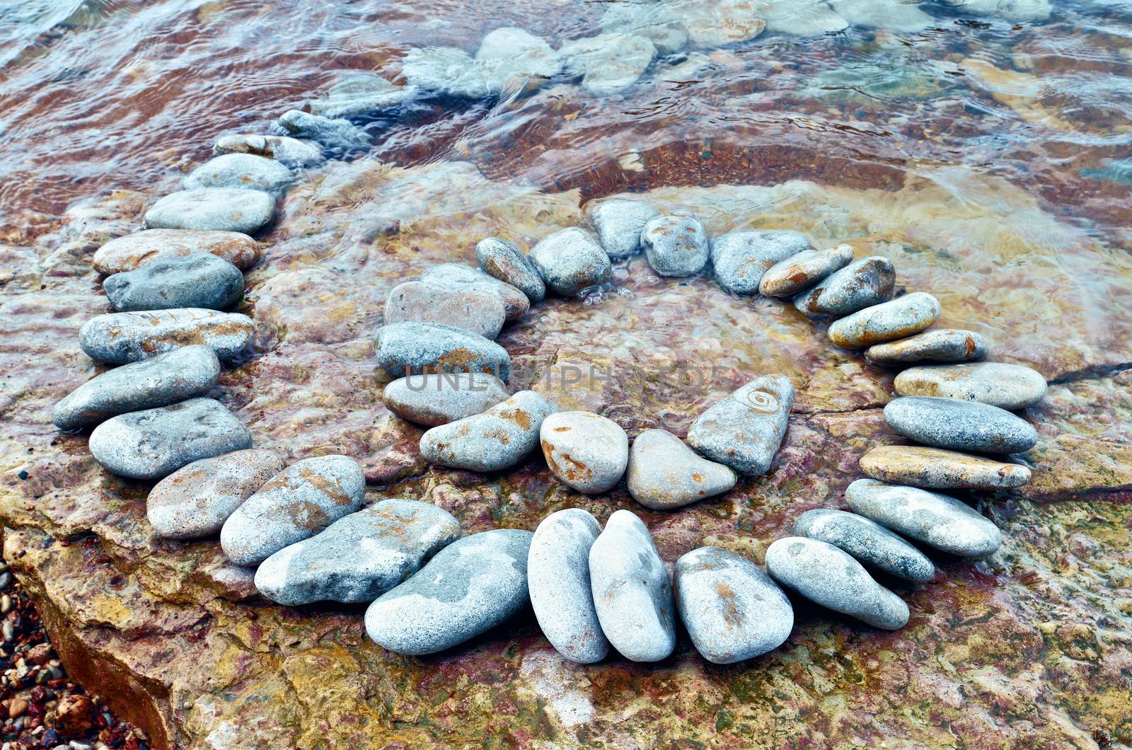 Spiral of white pebbles on the sea boulder