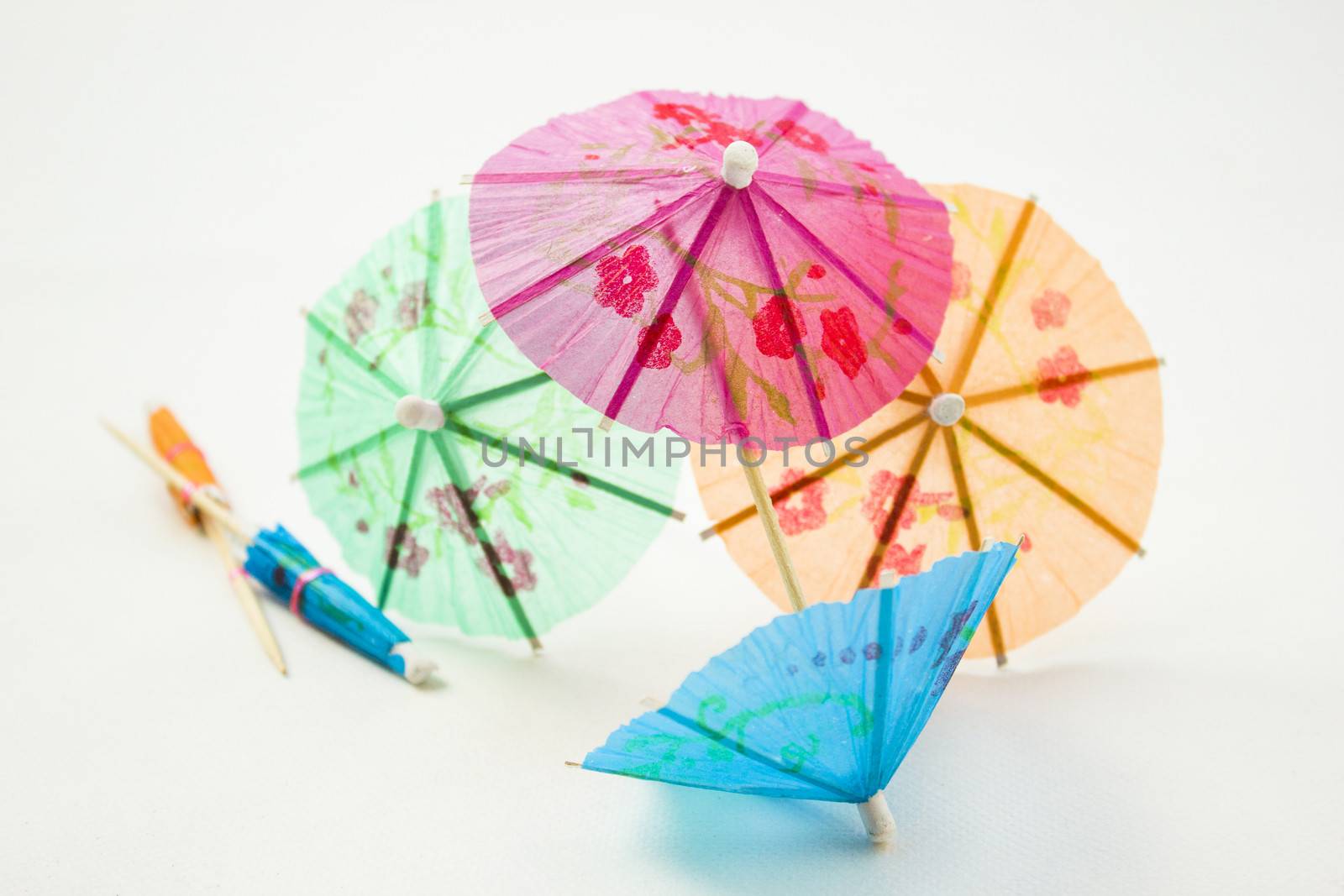 Different colors of cocktail umbrellas on a white background.