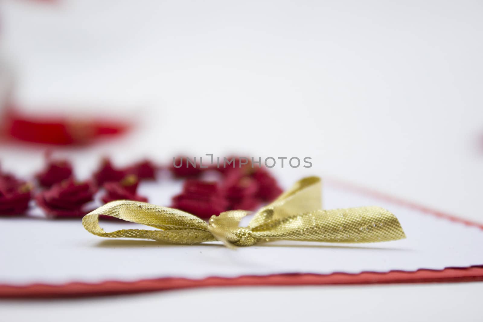 Handmake 3d origami card with a golden ribbon and background of red colored roses.